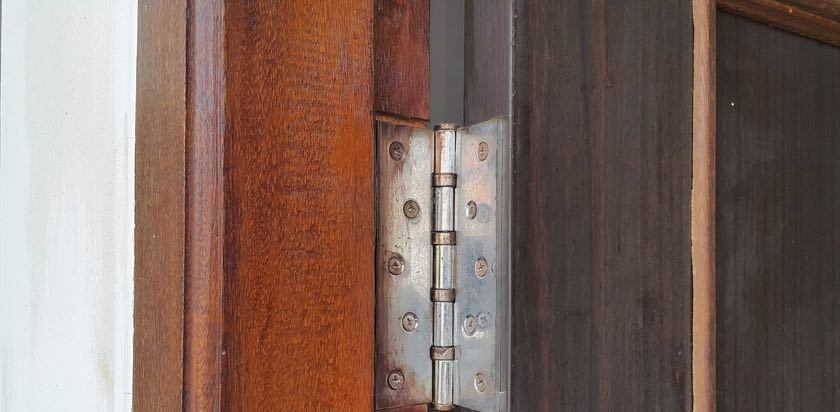 Detalhe de dobradiça em porta de madeira maciça